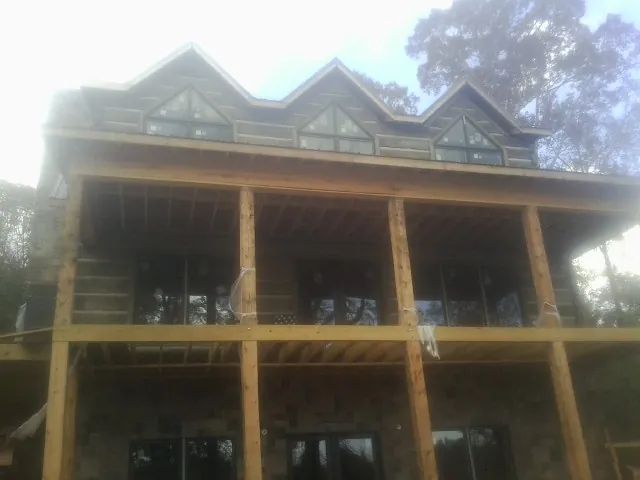 Dormers and porch framing on a large log home under construction — Roof Coating work by our crew in Dubuque
