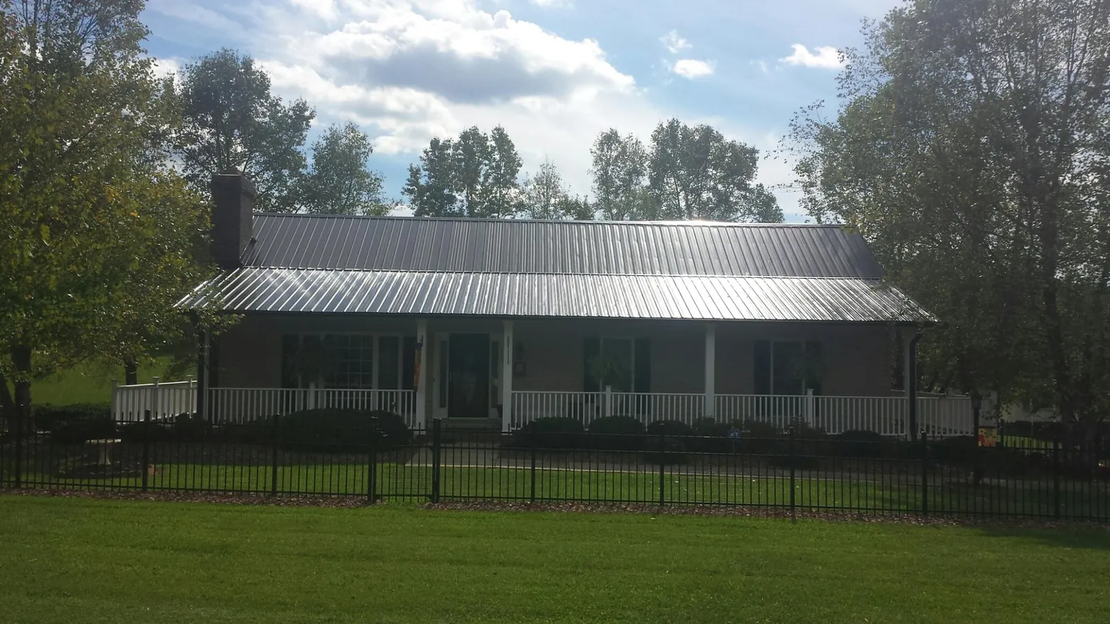 Gray metal roof on a brick ranch with a full width front porch — Gutter Guard Installation work by our crew in Dubuque