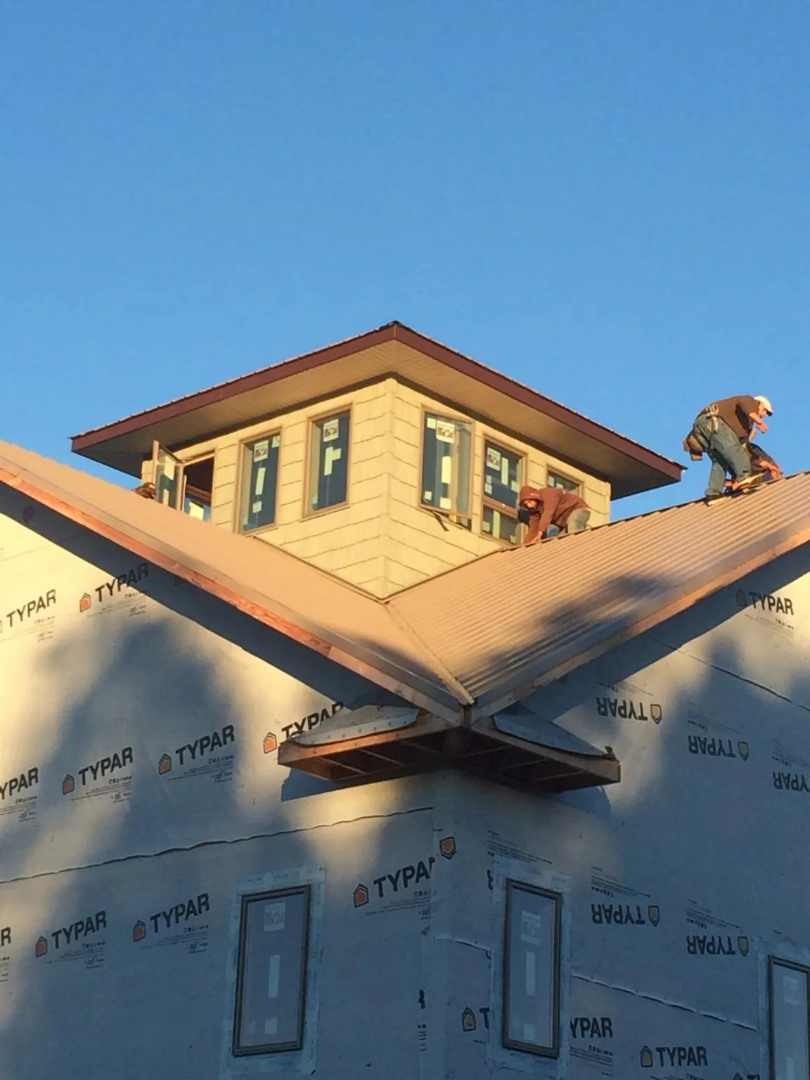Roofers working around a rooftop cupola on a new metal roof at sunset — Roof Waterproofing in Dubuque by Roofing Brothers